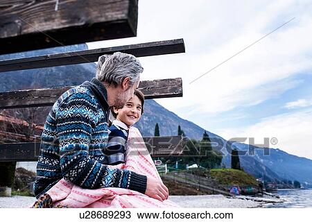 Boy and father wrapped in blanket on lakeside pier, side view, Lake Como, Onno, Lombardy, Italy View Large Photo Image Stock Image - Boy and father wrapped in blanket on lakeside pier, side view, Lake Como, Onno, Lombardy, Italy. Fotosearch