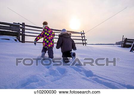 Boy and girl trudging through snow covered landscape, rear view View Large Photo Image Stock Image - Boy and girl trudging through snow covered landscape, rear view. Fotosearch