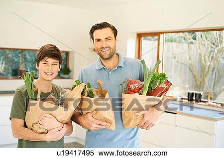 Boy and his father in kitchen holding grocery bags, portrait View Large Photo Image Stock Photography - Boy and his father in kitchen holding grocery bags, portrait. Fotosearch