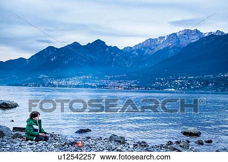 Boy by campfire at dusk, Onno, Lombardy, Italy View Large Photo Image Stock Photo - Boy by campfire at dusk, Onno, Lombardy, Italy. Fotosearch
