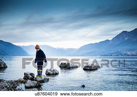 Stock Photo - Boy exploring around lakeside, Onno, Lombardy, Italy. Fotosearch