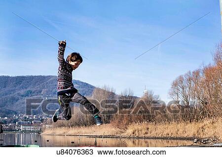 Boy jumping mid air on lakeside, Lake Como, Lecco, Lombardy, Italy View Large Photo Image Stock Image - Boy jumping mid air on lakeside, Lake Como, Lecco, Lombardy, Italy. Fotosearch