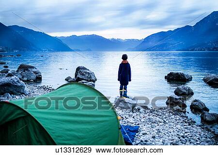 Stock Photo - Boy looking out over lake, rear view, Lake Como, Onno, Lombardy, Italy. Fotosearch