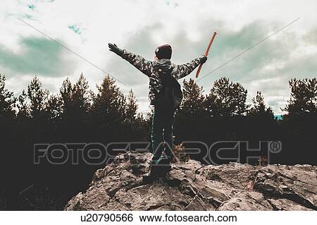 Stock Photograph - Boy on rock waving stick, Ural, Sverdlovsk, Russia. Fotosearch