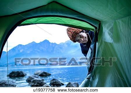 Stock Photo - Boy peering into tent by lakeside, Onno, Lombardy, Italy. Fotosearch