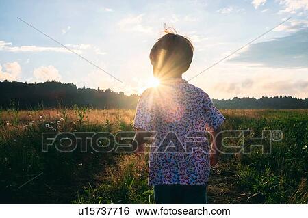 Stock Photograph - Boy playing in field at sunset. Fotosearch