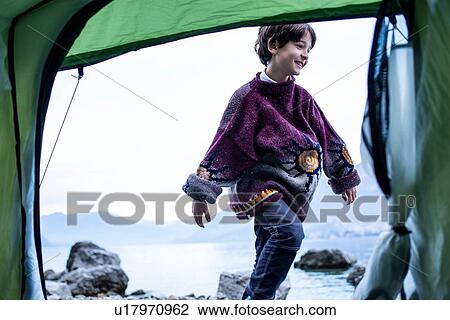 Stock Image - Boy playing outside tent on lakeside, Lake Como, Onno, Lombardy, Italy. Fotosearch