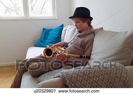Stock Photo - Boy practising saxophone on sofa. Fotosearch