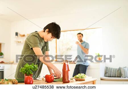 Boy preparing food at kitchen counter, father watching View Large Photo Image Stock Photo - Boy preparing food at kitchen counter, father watching. Fotosearch