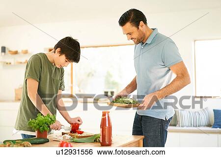 Boy slicing red pepper at kitchen counter, father watching View Large Photo Image Stock Photograph - Boy slicing red pepper at kitchen counter, father watching. Fotosearch