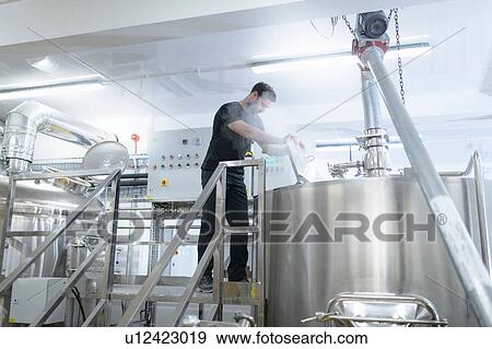 Stock Photo - Brewer inspecting brew mix in small brewery. Fotosearch