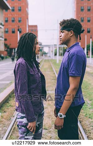 Stock Photo - Brother and sister face to face on tram tracks, Milan, Italy. Fotosearch