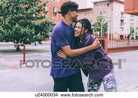Picture - Brother and sister hugging in town square, Milan, Italy. Fotosearch