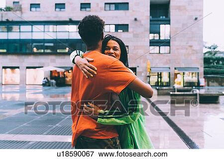 Stock Photo - Brother and sister hugging in town square, Milan, Italy. Fotosearch