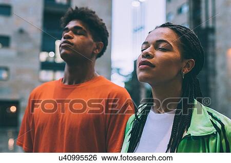 Stock Photograph - Brother and sister side by side with eyes closed, Milan, Italy. Fotosearch