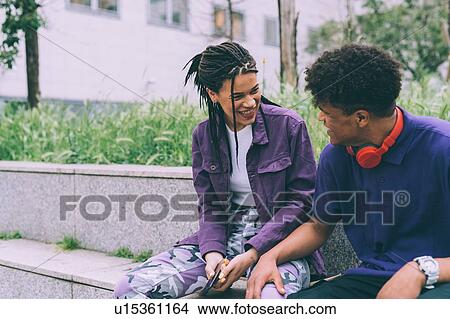 Picture - Brother and sister sitting and talking, Milan, Italy. Fotosearch