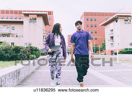 Stock Photography - Brother and sister walking and talking, Milan, Italy. Fotosearch