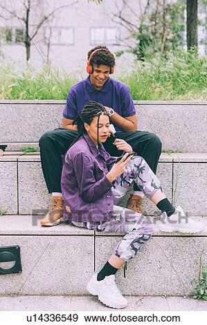 Stock Photo - Brother and sister watching footage on mobile phone together, Milan, Italy. Fotosearch