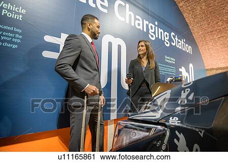 Businessman and businesswoman at electric vehicle charging station, Manchester, UK View Large Photo Image Stock Image - Businessman and businesswoman at electric vehicle charging station, Manchester, UK. Fotosearch