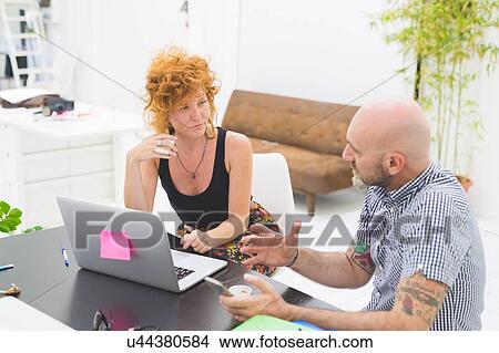 Picture - Businessman and woman having meeting and discussion at office desk. Fotosearch