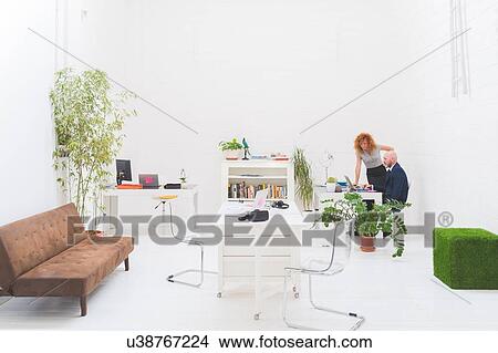 Businessman and woman looking at laptop in office meeting View Large Photo Image Picture - Businessman and woman looking at laptop in office meeting. Fotosearch