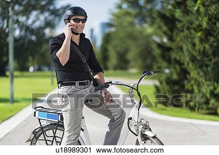 Businessman on electric bicycle talking on the phone View Large Photo Image Stock Image - Businessman on electric bicycle talking on the phone. Fotosearch