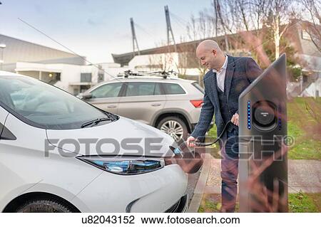 Businessman plugging in electric car at charging point, Manchester, UK View Large Photo Image Stock Image - Businessman plugging in electric car at charging point, Manchester, UK. Fotosearch