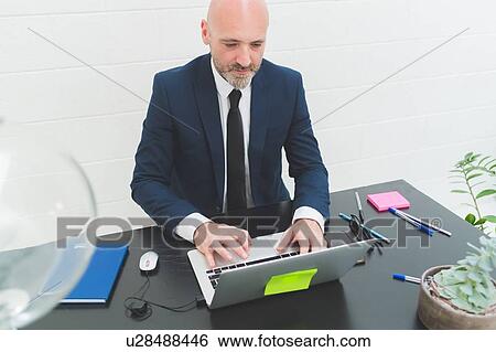 Businessman typing at laptop on office desk View Large Photo Image Stock Photograph - Businessman typing at laptop on office desk. Fotosearch