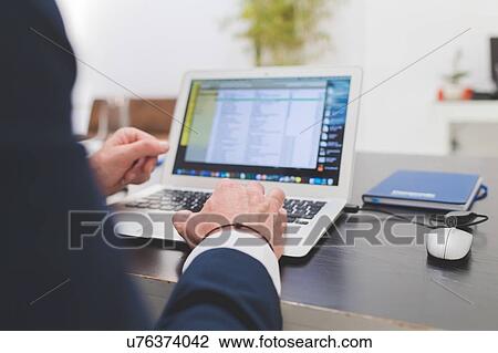 Businessman typing on laptop at office desk, over shoulder view View Large Photo Image Stock Image - Businessman typing on laptop at office desk, over shoulder view. Fotosearch
