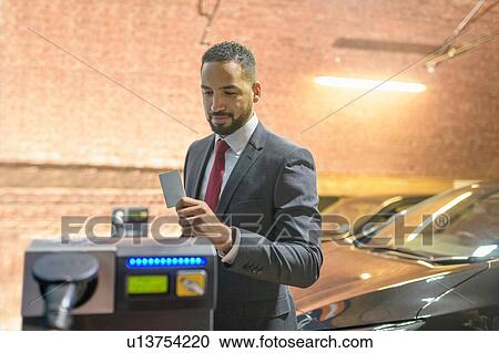 Businessman using access card at electric vehicle charging station, Manchester, UK View Large Photo Image Stock Image - Businessman using access card at electric vehicle charging station, Manchester, UK. Fotosearch