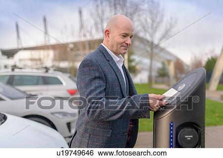 Businessman using access card at electric car charging point, Manchester, UK View Large Photo Image Stock Photograph - Businessman using access card at electric car charging point, Manchester, UK. Fotosearch