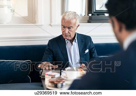 Stock Photo - Businessman using digital tablet in restaurant. Fotosearch