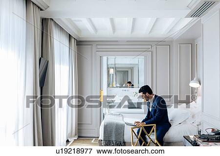 Stock Photo - Businessman using laptop in suite. Fotosearch