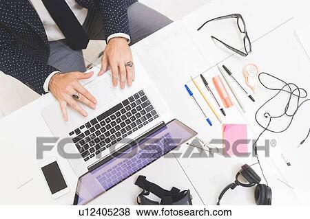 Businessman using laptop on office desk, overhead view View Large Photo Image Stock Photo - Businessman using laptop on office desk, overhead view. Fotosearch