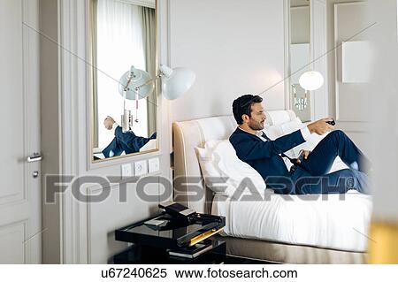 Stock Photography - Businessman using remote control in suite. Fotosearch