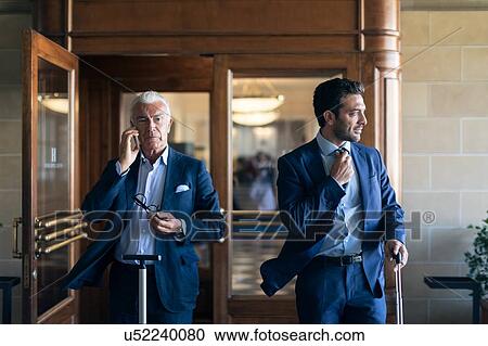Businessman using smartphone and leaving office with colleague View Large Photo Image Stock Image - Businessman using smartphone and leaving office with colleague. Fotosearch