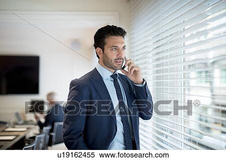 Businessman using smartphone beside window View Large Photo Image Stock Photography - Businessman using smartphone beside window. Fotosearch
