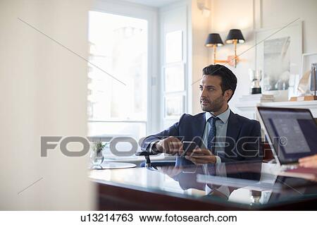 Stock Image - Businessman using smartphone in office. Fotosearch