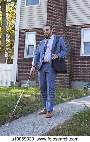 Stock Image - Businessman with visual impairment outside with his cane. Fotosearch