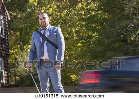 Stock Photography - Businessman with visual impairment outside with his cane. Fotosearch