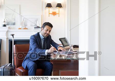 Stock Image - Businessman writing on digital tablet in office. Fotosearch
