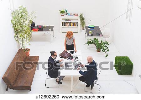 Businessmen and woman using laptops at office meeting, high angle view View Large Photo Image Stock Image - Businessmen and woman using laptops at office meeting, high angle view. Fotosearch