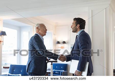 Picture - Businessmen shaking hands in office. Fotosearch