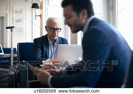 Stock Photo - Businessmen using digital tablet and laptop in office. Fotosearch