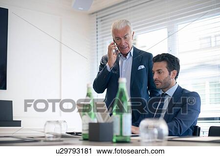 Businessmen using smartphone and laptop in office View Large Photo Image Stock Image - Businessmen using smartphone and laptop in office. Fotosearch