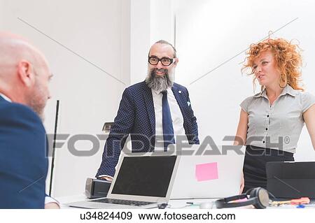 Businesswoman and men chatting over office desk View Large Photo Image Stock Photo - Businesswoman and men chatting over office desk. Fotosearch