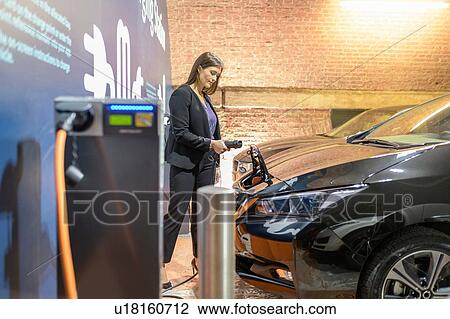 Businesswoman plugging in car at electric vehicle charging station, Manchester, UK View Large Photo Image Stock Image - Businesswoman plugging in car at electric vehicle charging station, Manchester, UK. Fotosearch