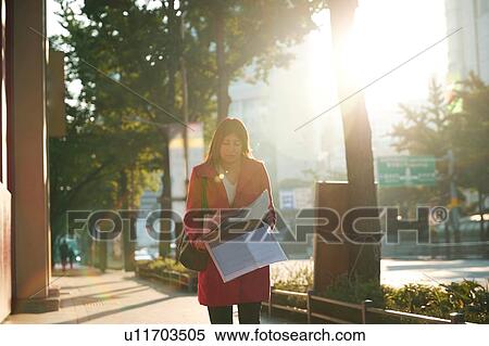 Stock Photography - Businesswoman reading newspapers in city, Seoul, South Korea. Fotosearch