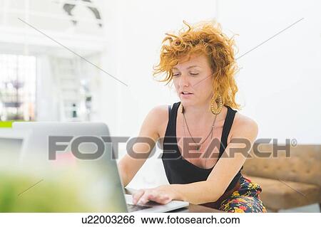 Stock Photograph - Businesswoman typing on laptop at office desk. Fotosearch