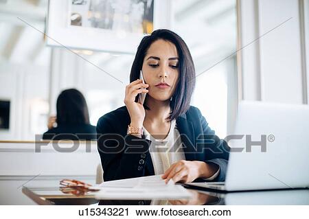 Stock Image - Businesswoman using smartphone and laptop in suite. Fotosearch